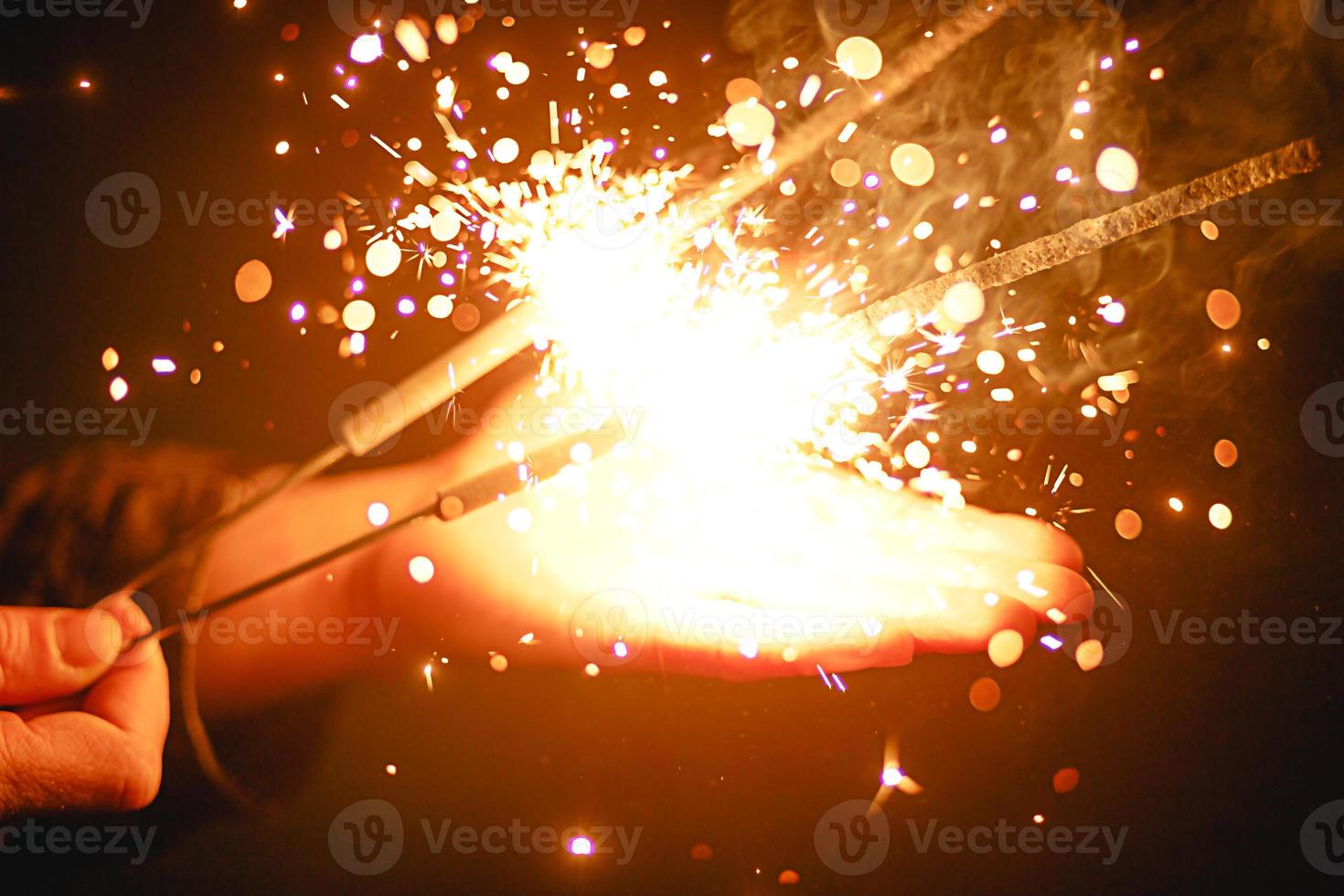 Sparks and light from sparklers in the dark on the palm of a person. Christmas magic, new year's eve, festive background. Space for text photo