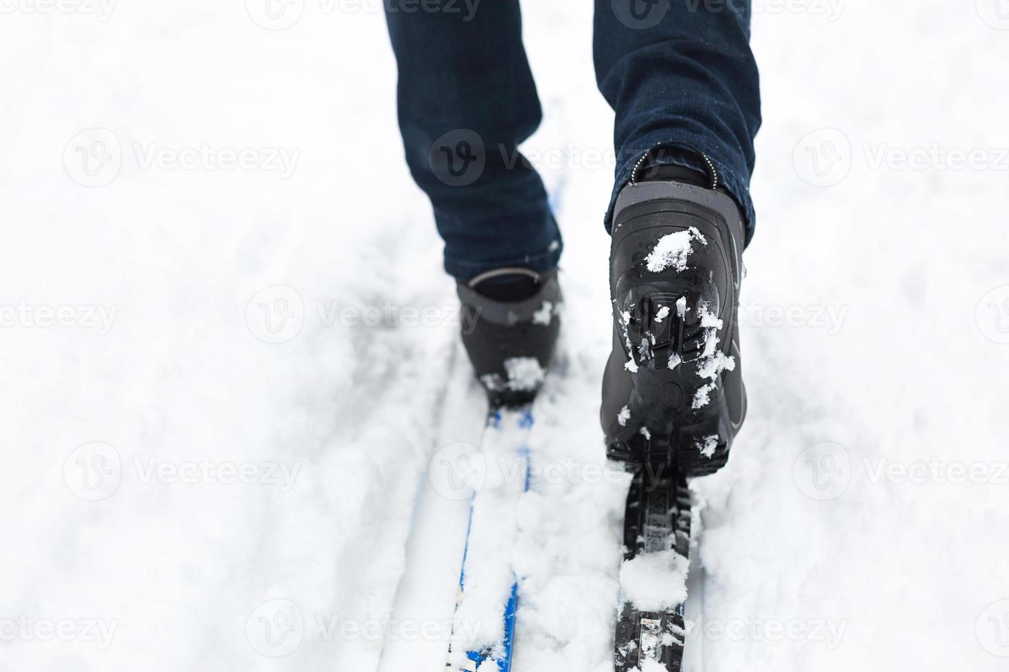Feet of a skier in ski boots on cross-country skis. Walking in the snow, winter sports, healthy lifestyle. Close-up, copyspace photo