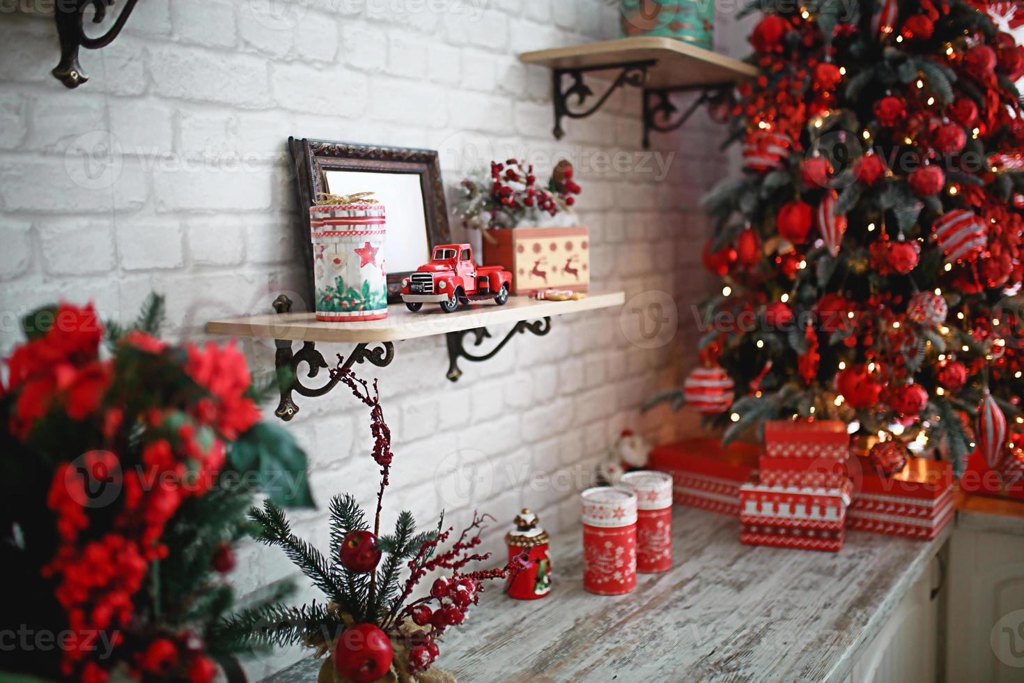 Gifts in boxes close-up under a Christmas tree with red and white decor in a white living room. New year, European style, kitchen decor. Space for text, selective focus on the car photo