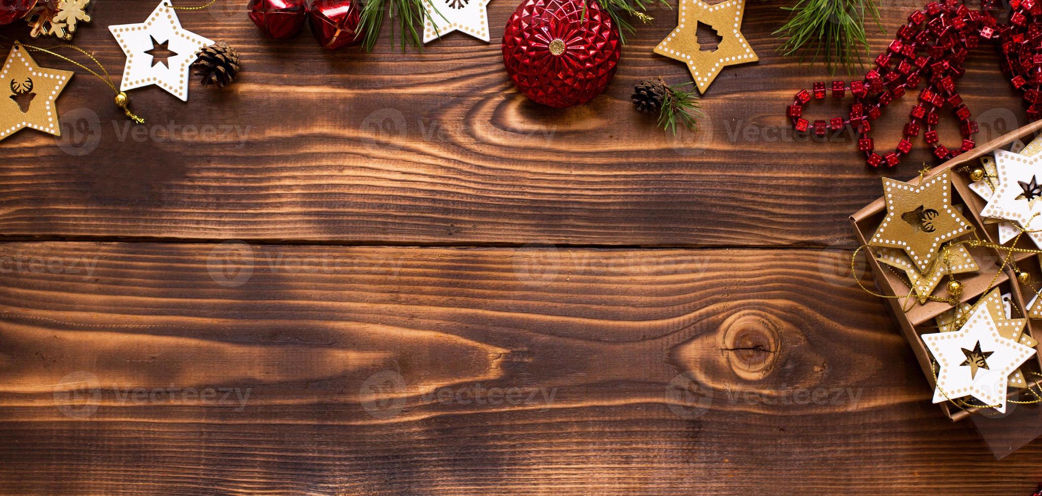 marco con decoración navideña sobre un fondo de madera. año nuevo, ambiente festivo, ramas de abeto verde, estrellas decorativas, caja de regalo, cuentas, bolas, campanas, conos. espacio para texto, plano foto