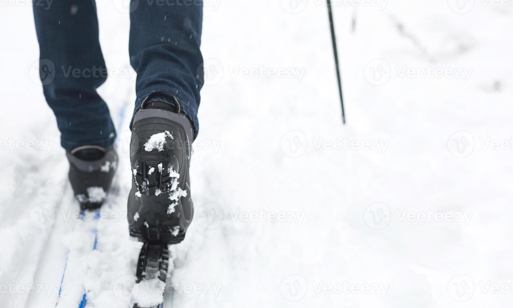 Feet of a skier in ski boots on cross-country skis. Walking in the snow, winter sports, healthy lifestyle. Close-up, copyspace photo