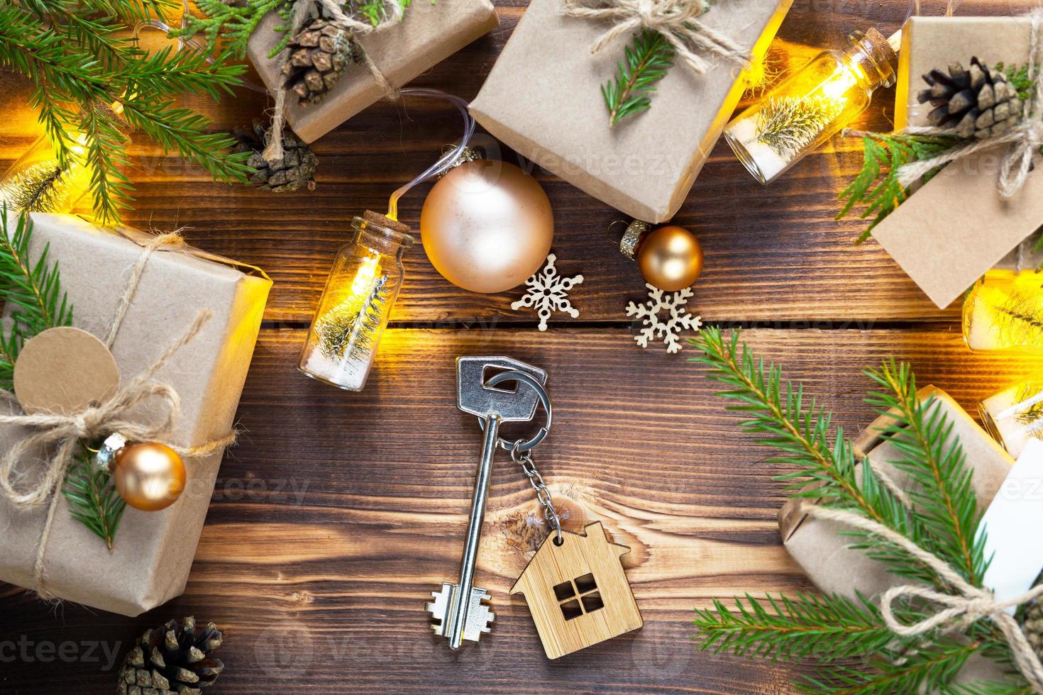 la llave de la casa sobre un fondo natural con una caja con un regalo para navidad y año nuevo. vivienda ecológica, hipoteca, préstamo, reserva, compra de bienes inmuebles, mudarse a su casa foto