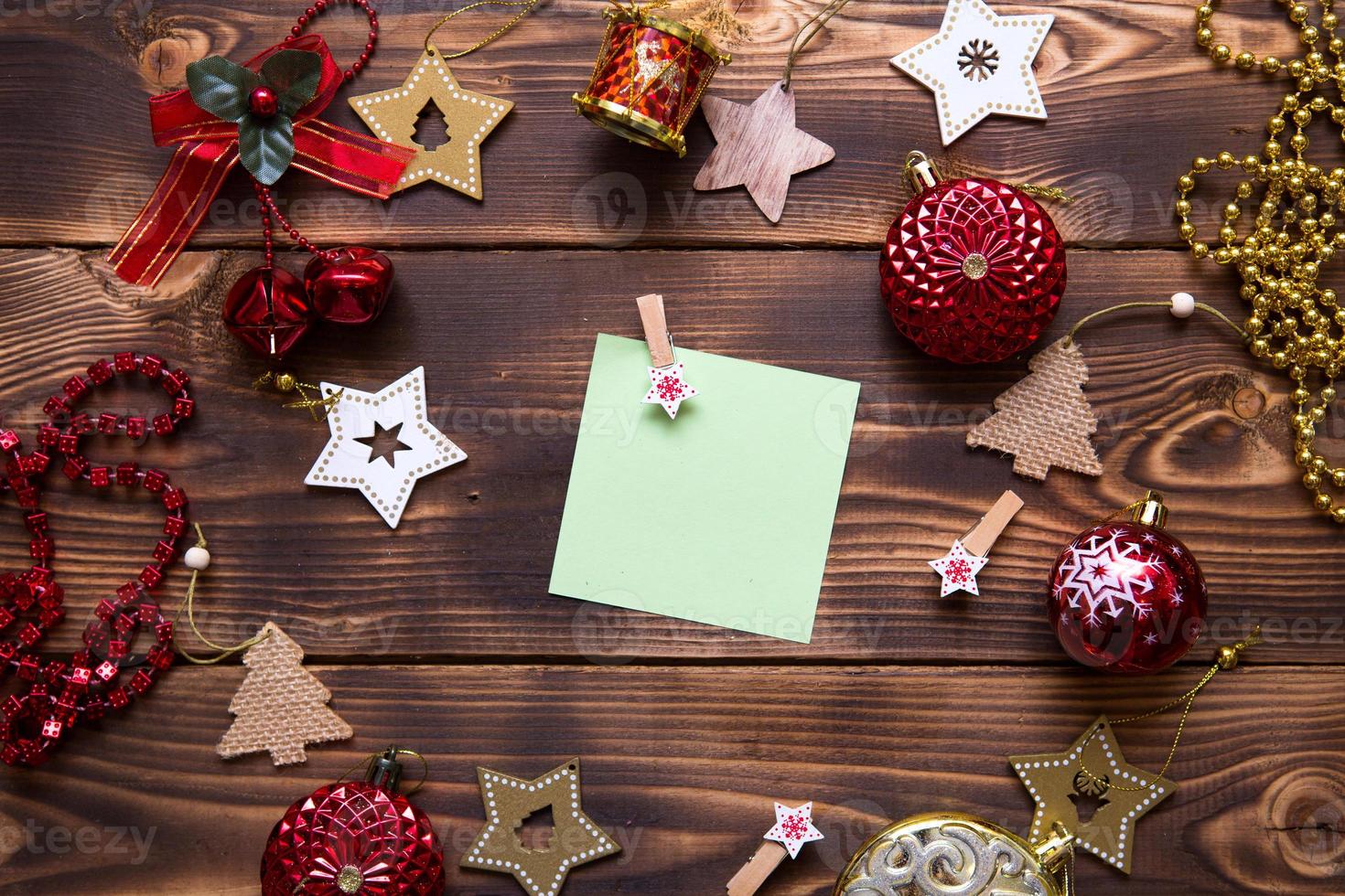 Christmas flat lay of red balloons and wooden stars and clothespins on a dark background with a square sheet for notes in the center. New year's frame, space for text. Xmas toys, beads, pine branches photo