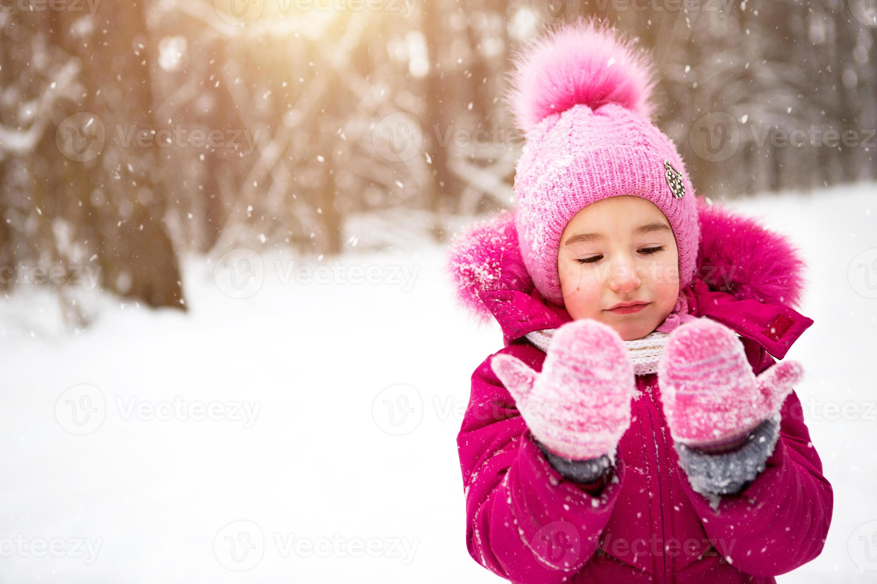 Niña jugando con nieve niña en guantes mantenga bola de nieve invierno  mujer sonriente en ropa de abrigo con