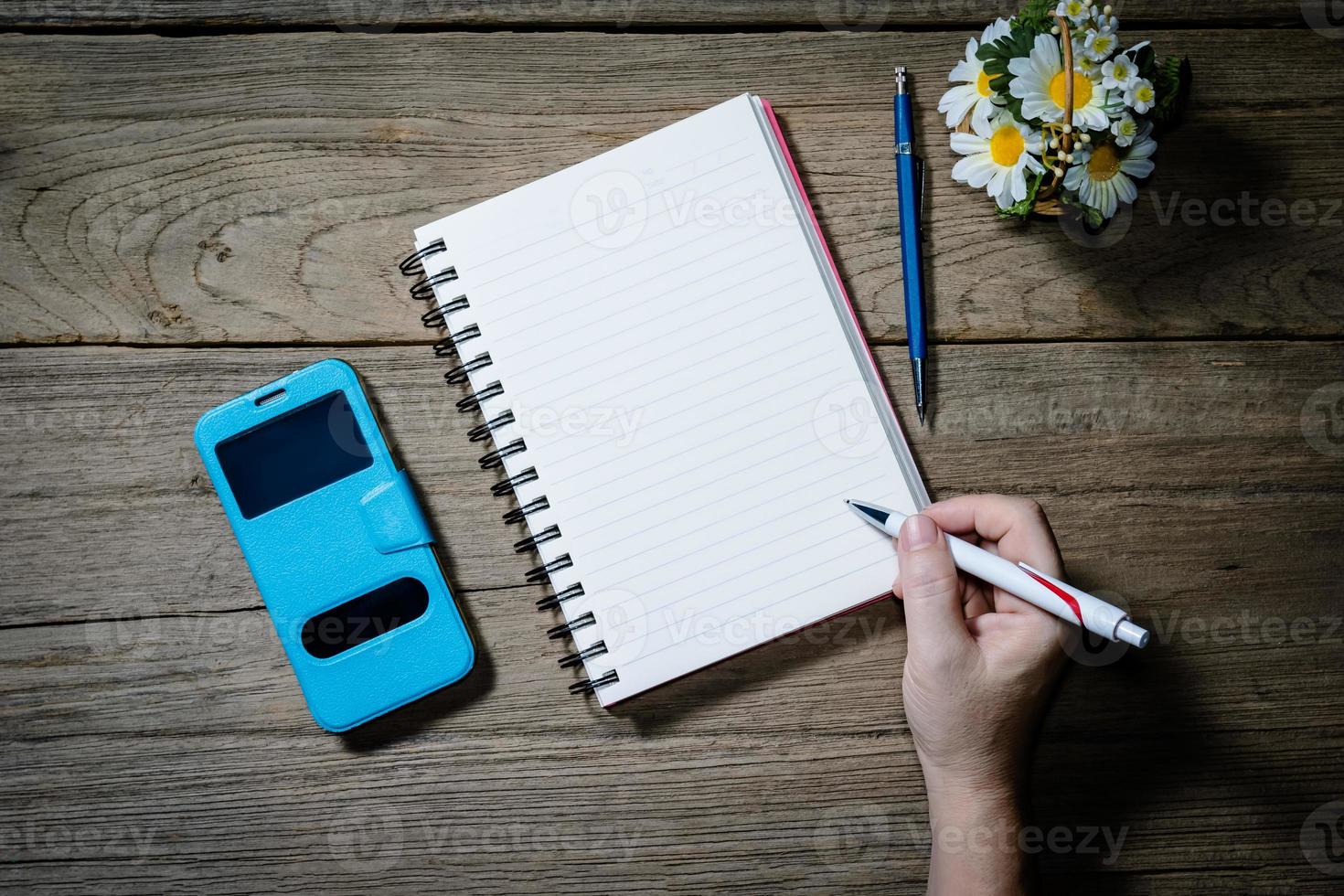 Human hand holding pen with open note book photo