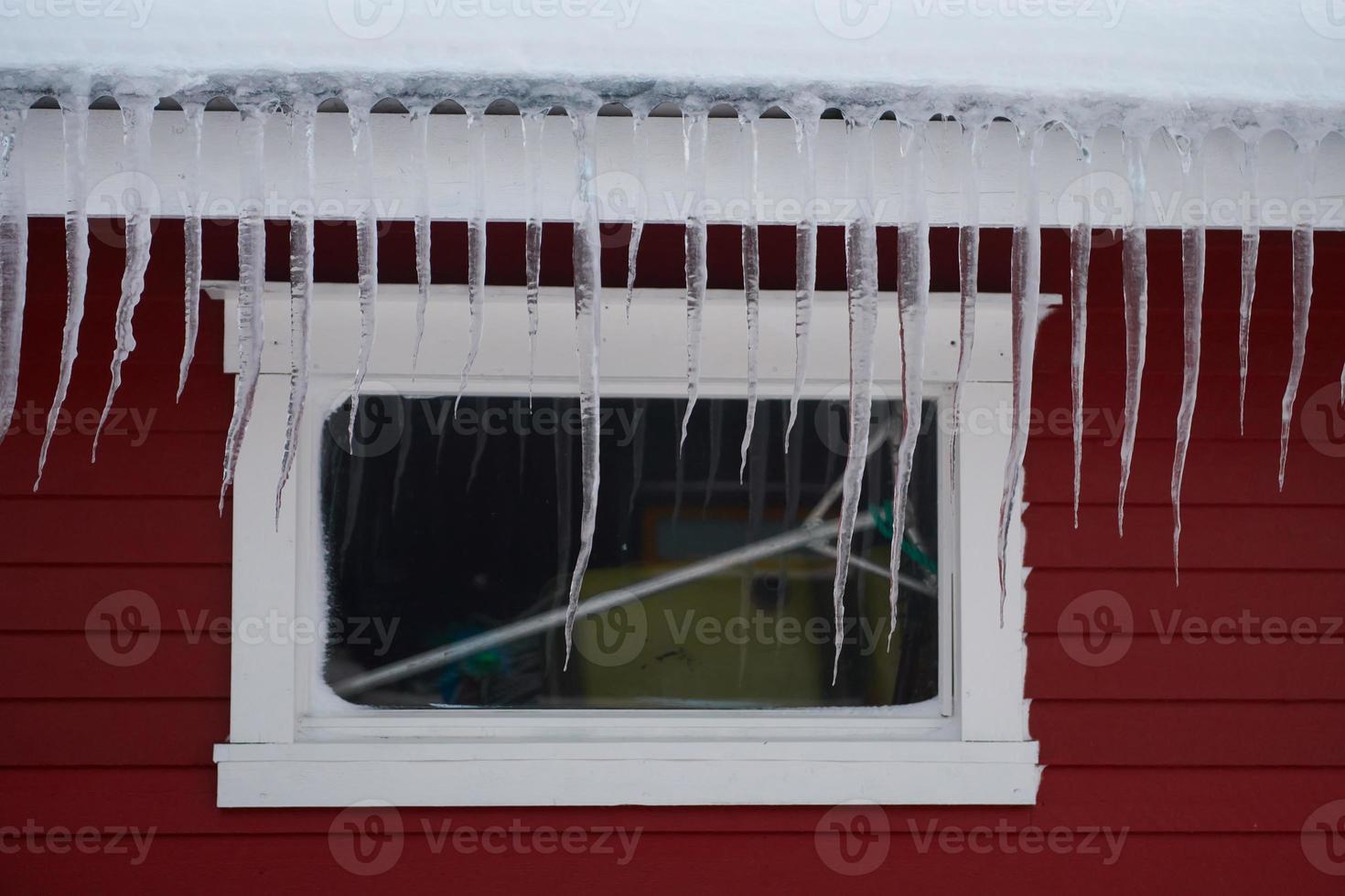 icicles on the roof of a red house in Norway photo