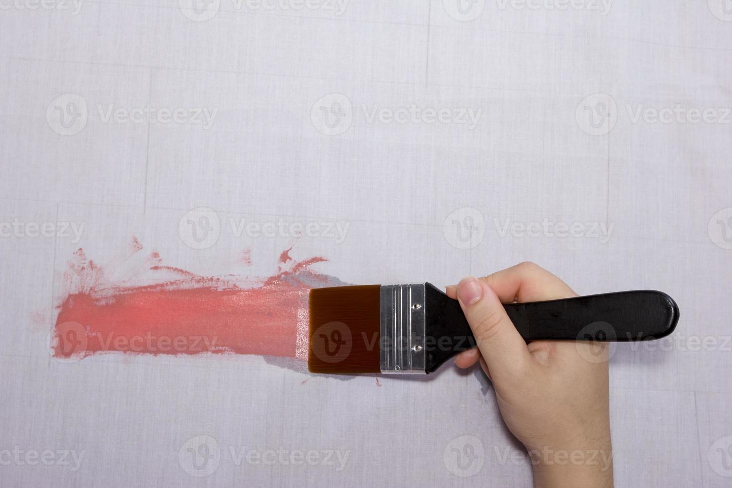 hand holding paintbrush paint on gray cloth photo