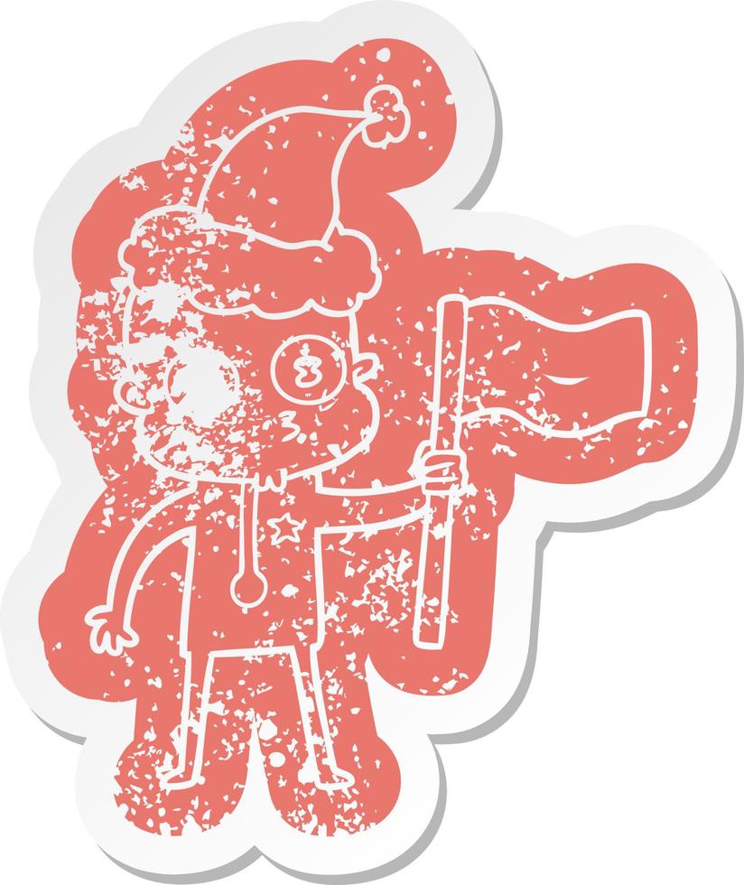 cartoon distressed sticker of a weird bald spaceman with flag wearing santa hat vector