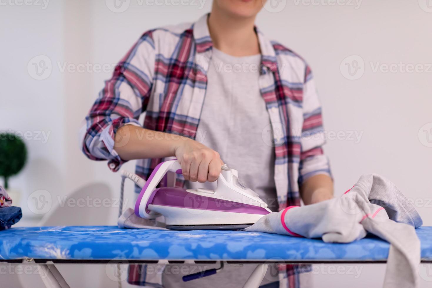 Red haired woman ironing clothes at home photo