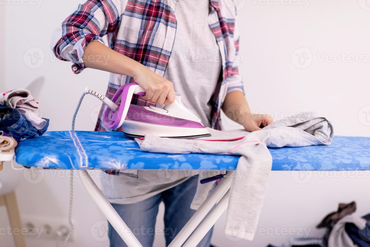 Red haired woman ironing clothes at home photo