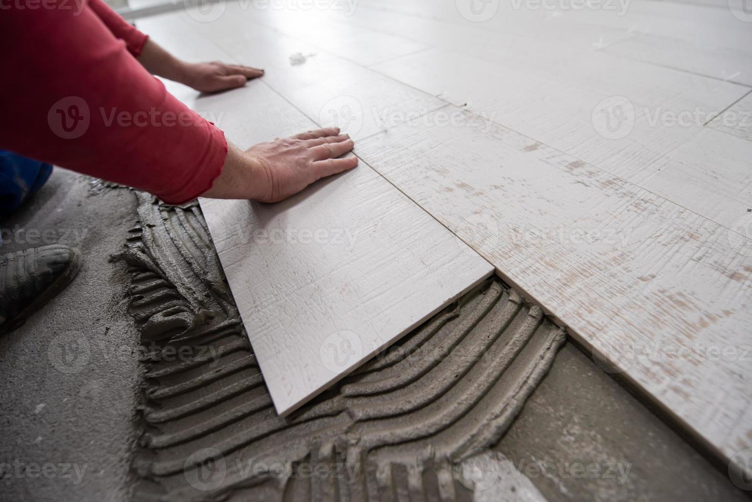 worker installing the ceramic wood effect tiles on the floor photo