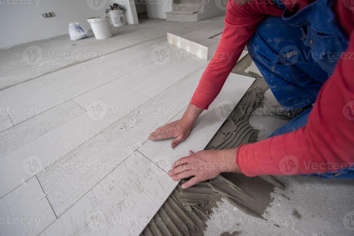 worker installing the ceramic wood effect tiles on the floor photo