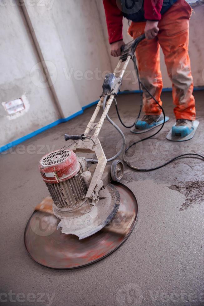 worker performing and polishing sand and cement screed floor photo