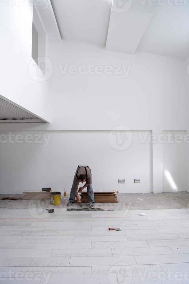 trabajador instalando las baldosas cerámicas con efecto madera en el suelo foto