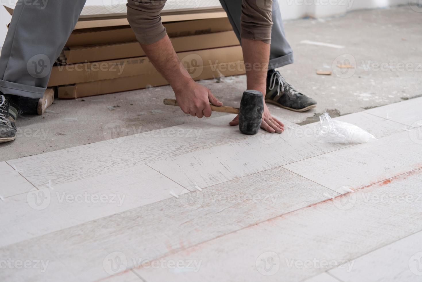 worker installing the ceramic wood effect tiles on the floor photo