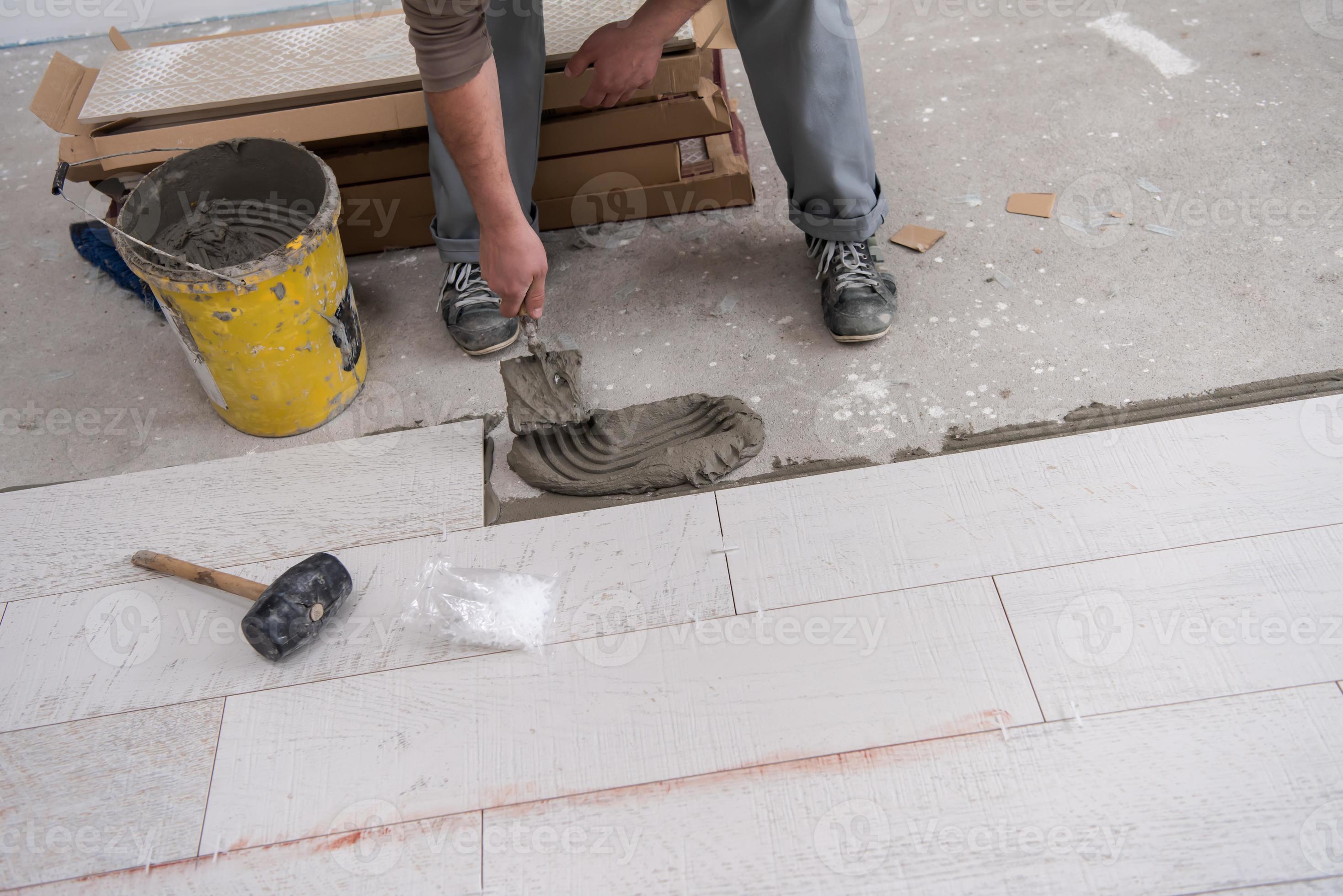 worker installing the ceramic wood effect tiles on the floor 10741814