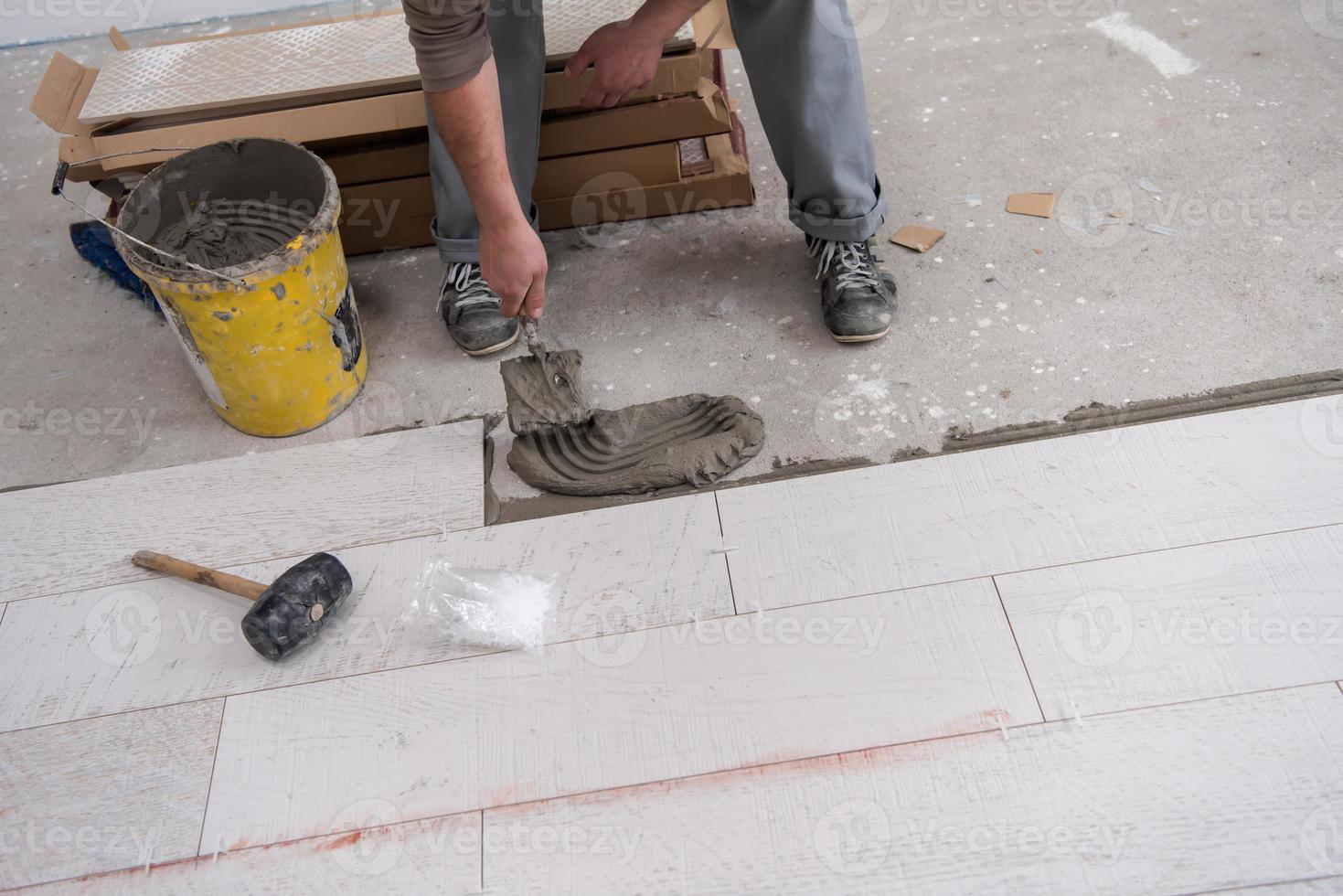 worker installing the ceramic wood effect tiles on the floor photo