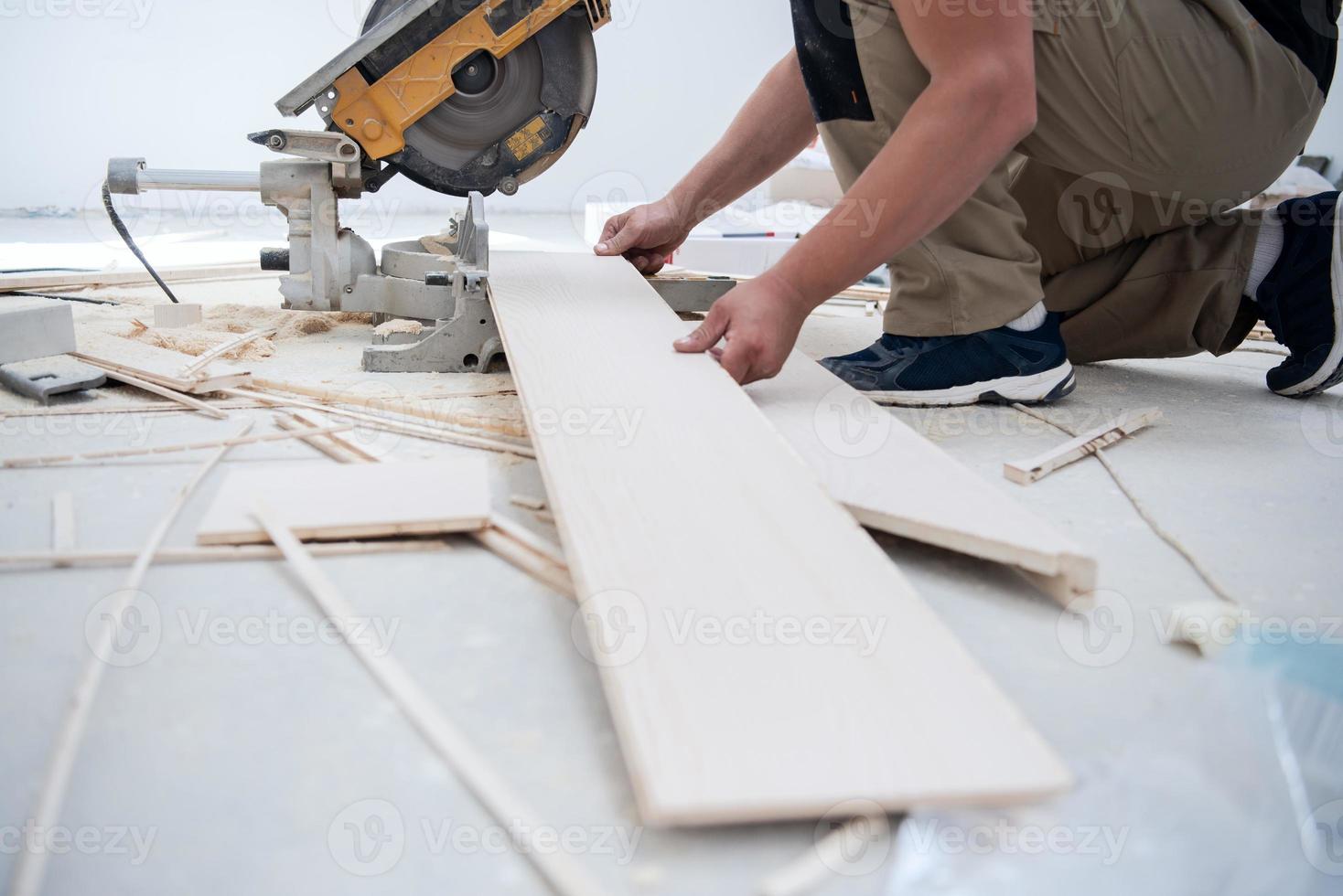 Man cutting laminate floor plank with electrical circular saw photo