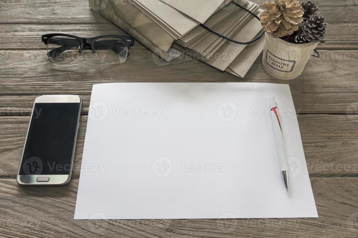 White paper with pen,bucket,smartphone,bag,glasses on wooden table photo