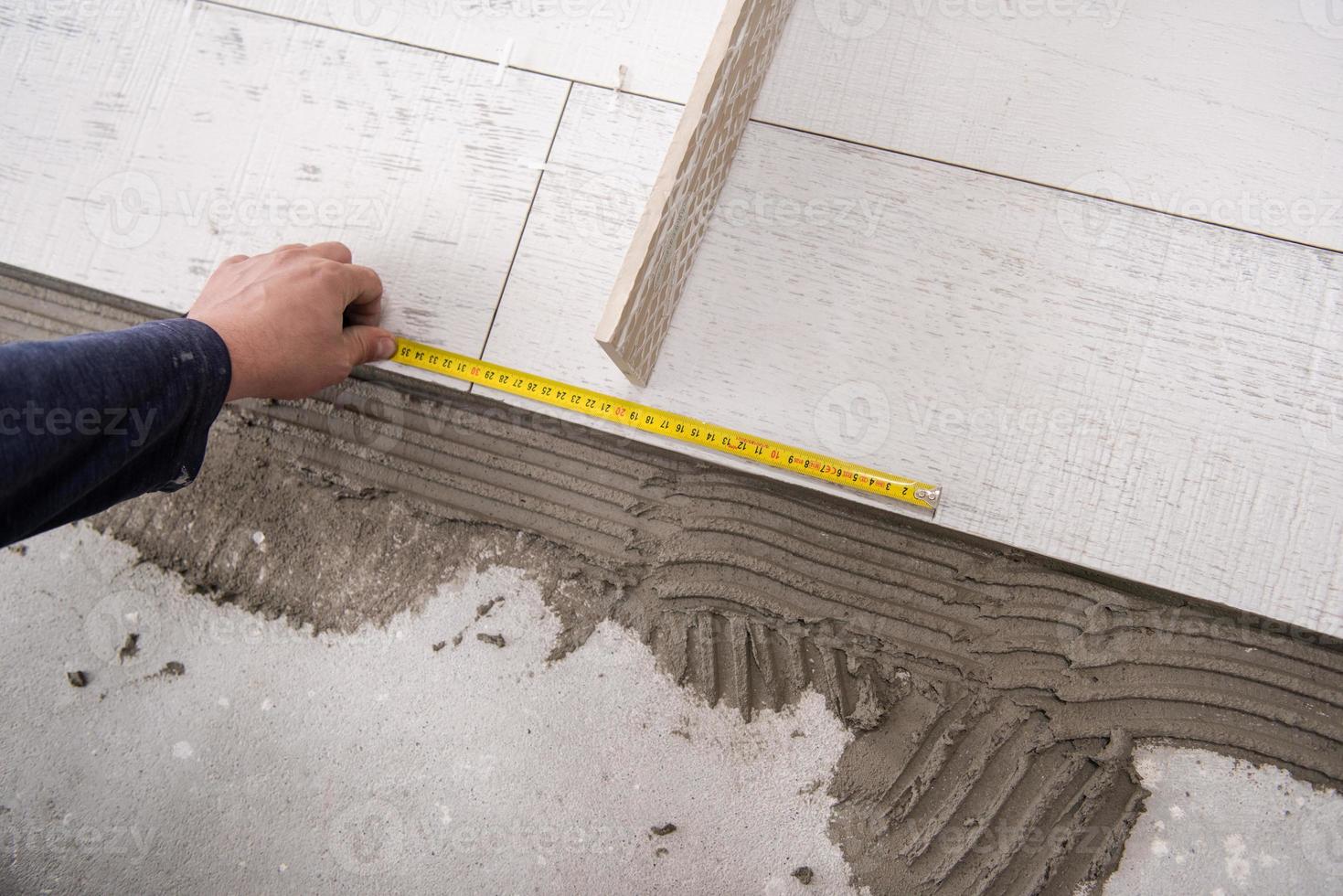 worker installing the ceramic wood effect tiles on the floor photo