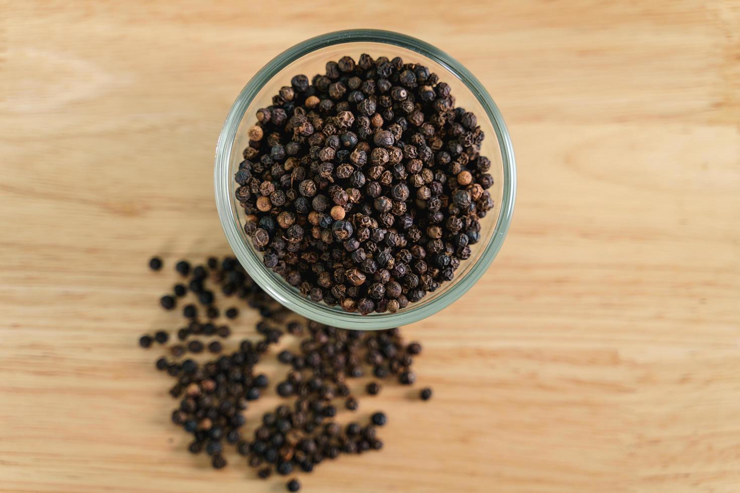 pimienta negra en un recipiente de vidrio sobre la mesa de madera. concepto de comida, especias, condimentos. foto