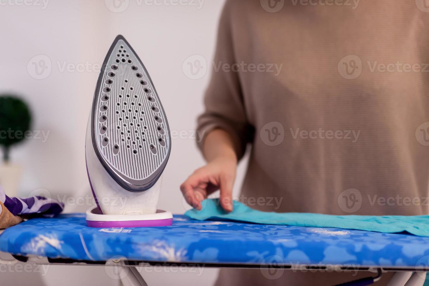 Red haired woman ironing clothes at home photo