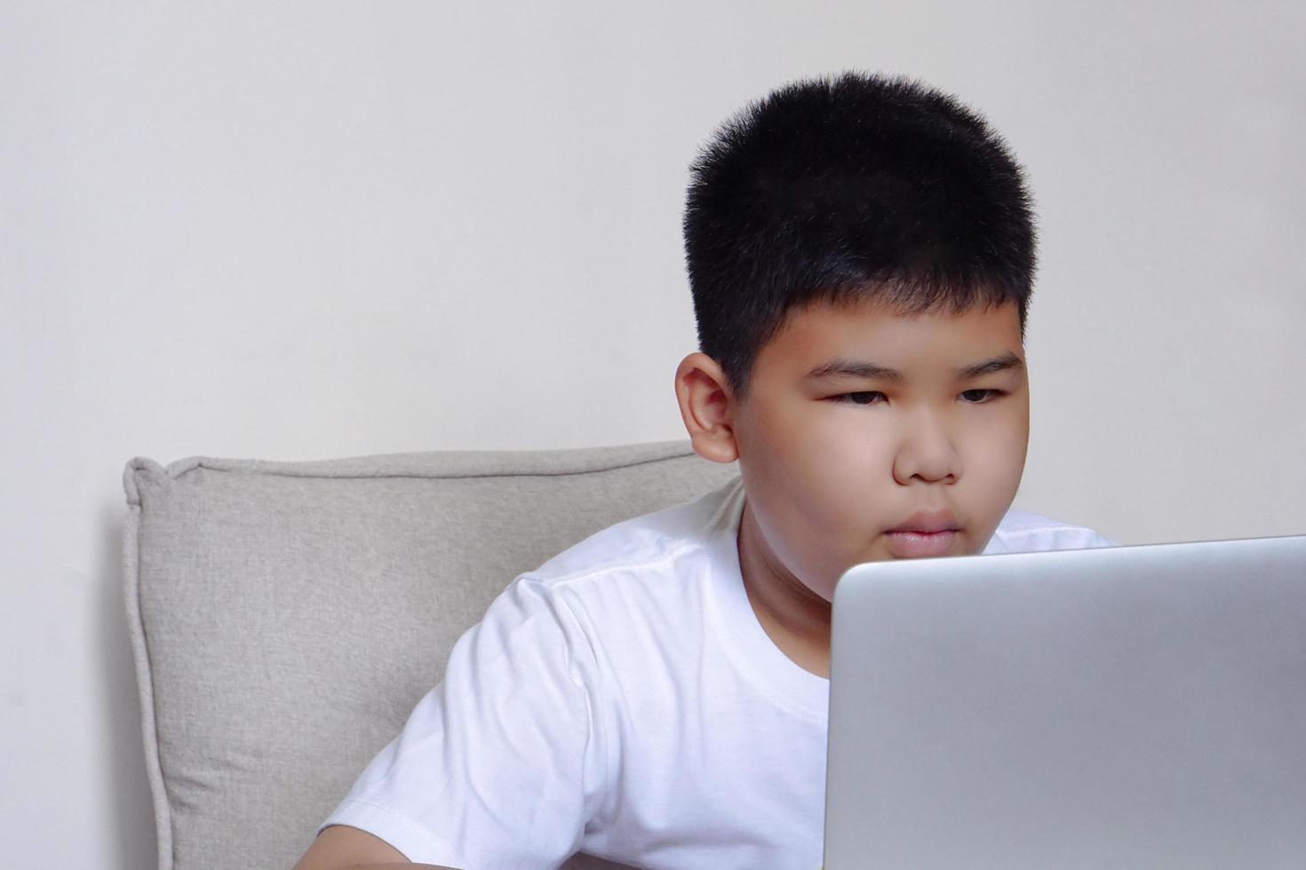 Close up face cute boy having fun watching laptop. Education, learning and technology concept. photo