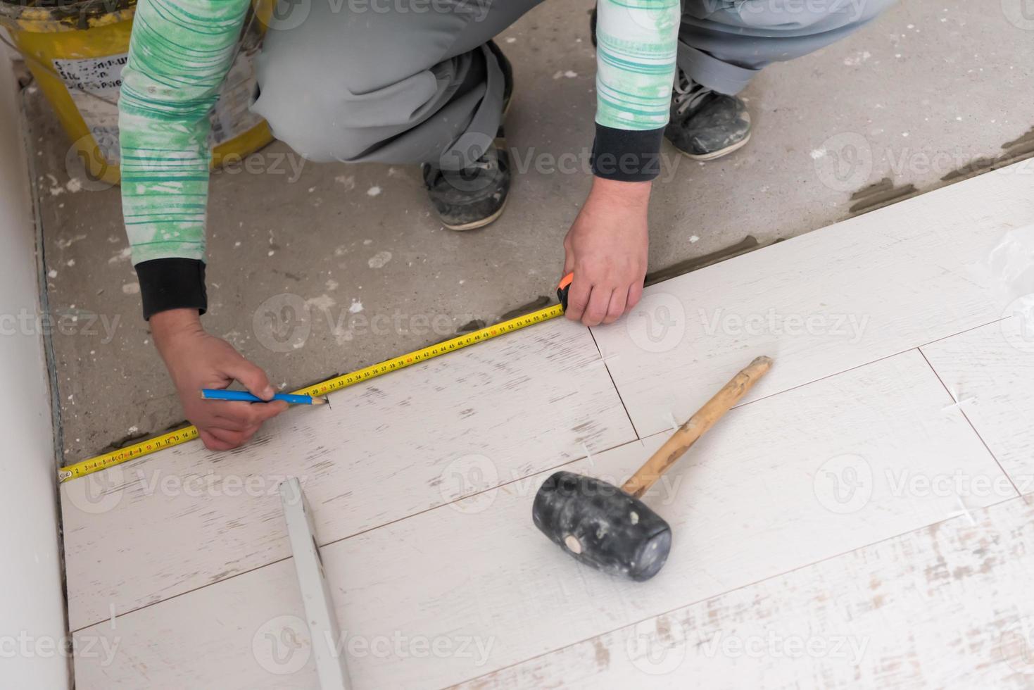 worker installing the ceramic wood effect tiles on the floor photo