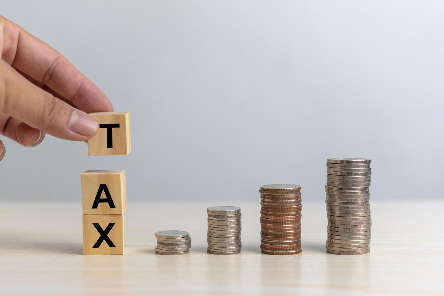 Hand holding wood cube block TAX and coin money on desk. Business finance accounting income concept. photo