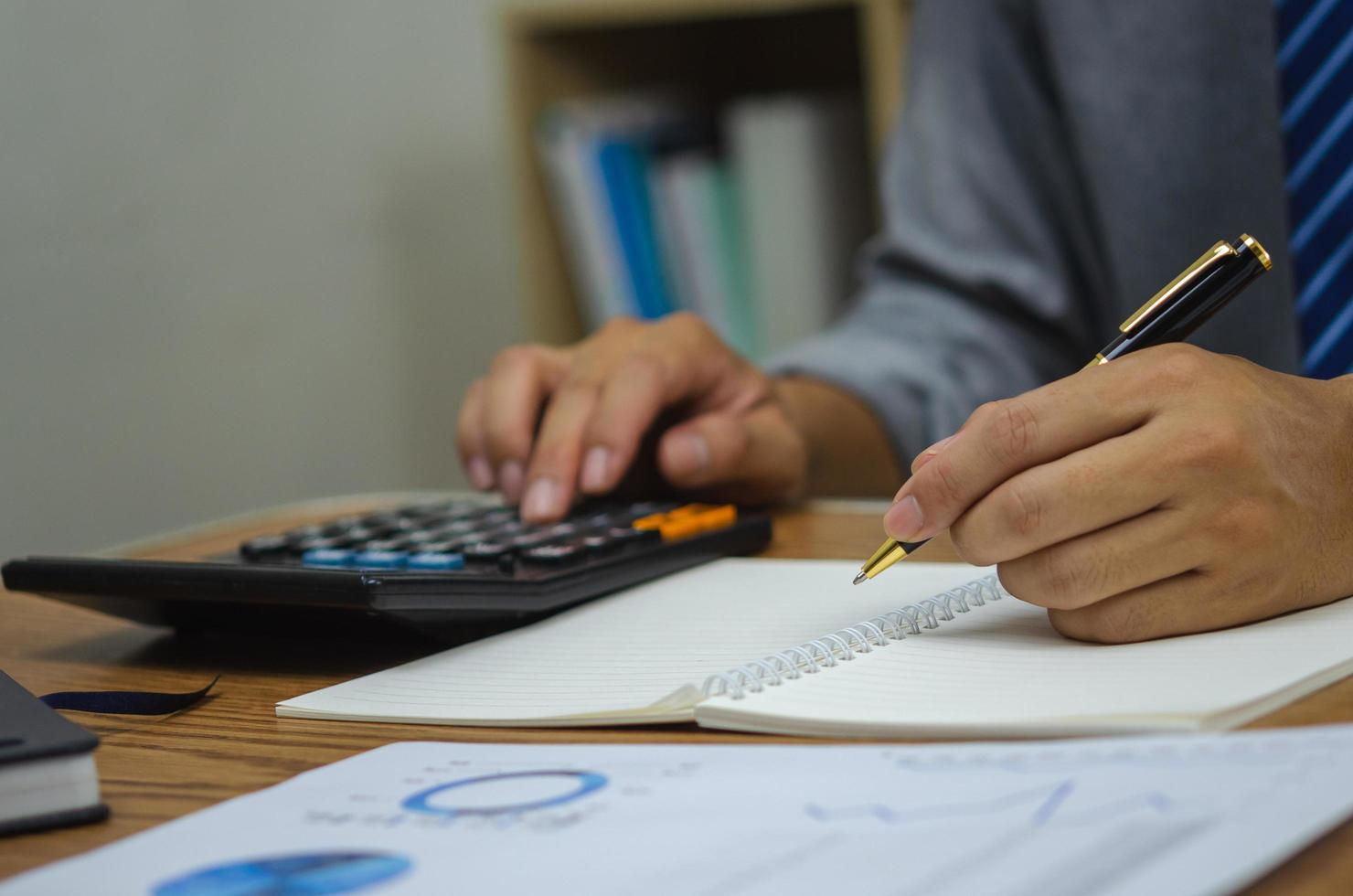 hombre mano sosteniendo pluma escribir libro análisis negocio inversión finanzas gráfico informe sobre la mesa. foto