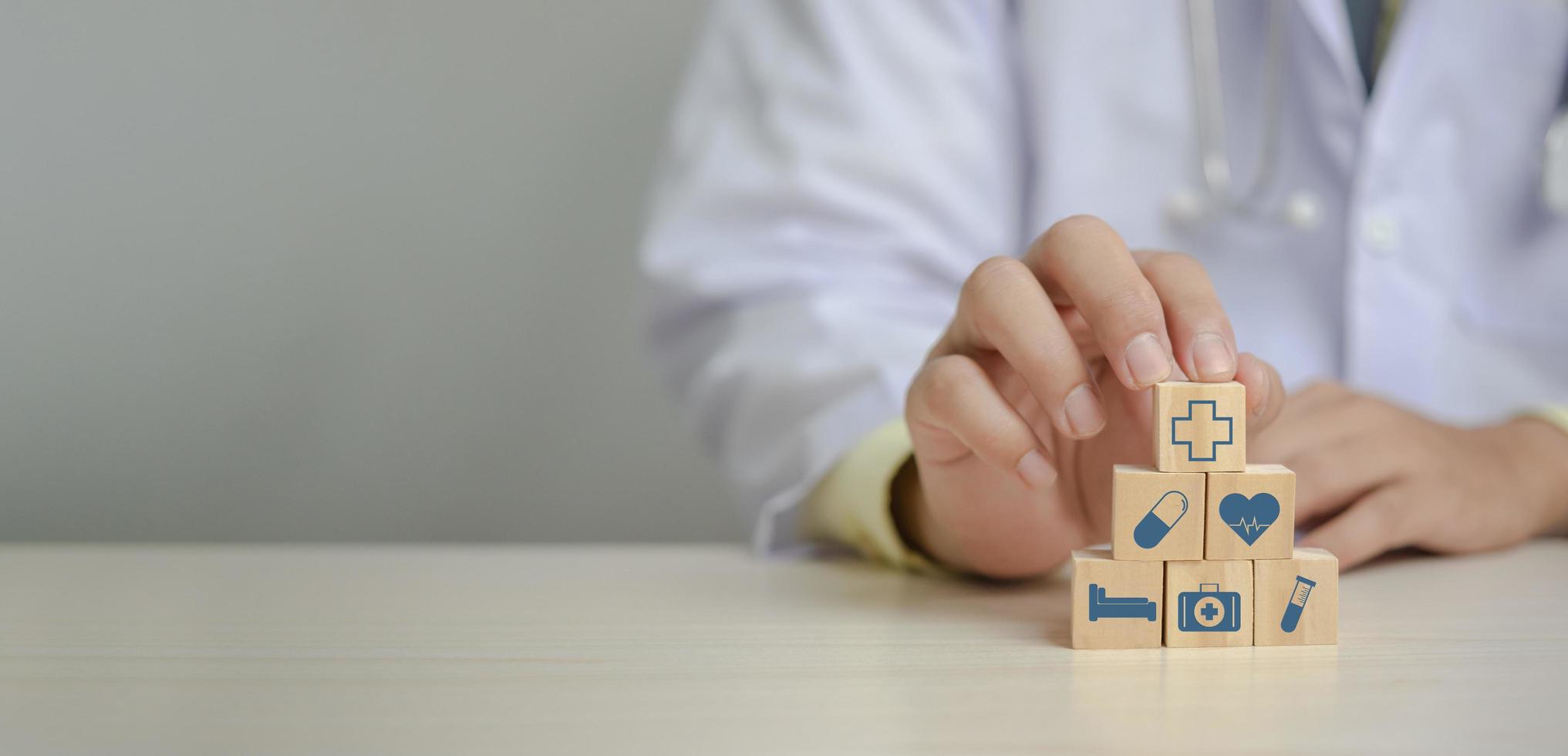 Doctor putting and stacking wooden block cube icon symbol medical health care on table panorama background concept. photo