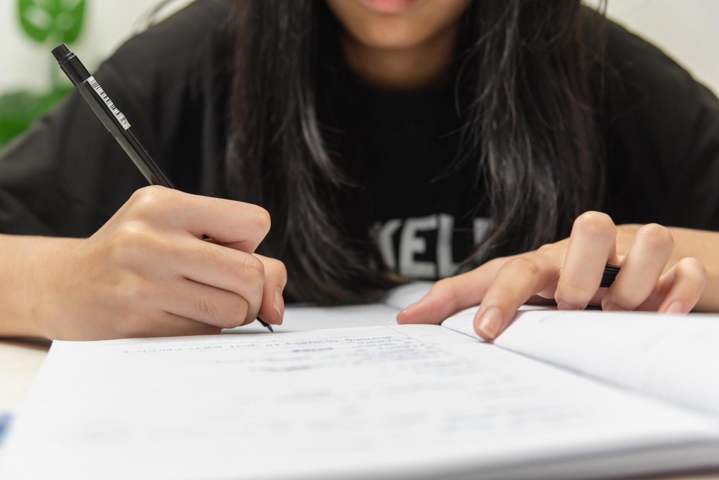 Asian student girl is writing homework and reading book at desk photo