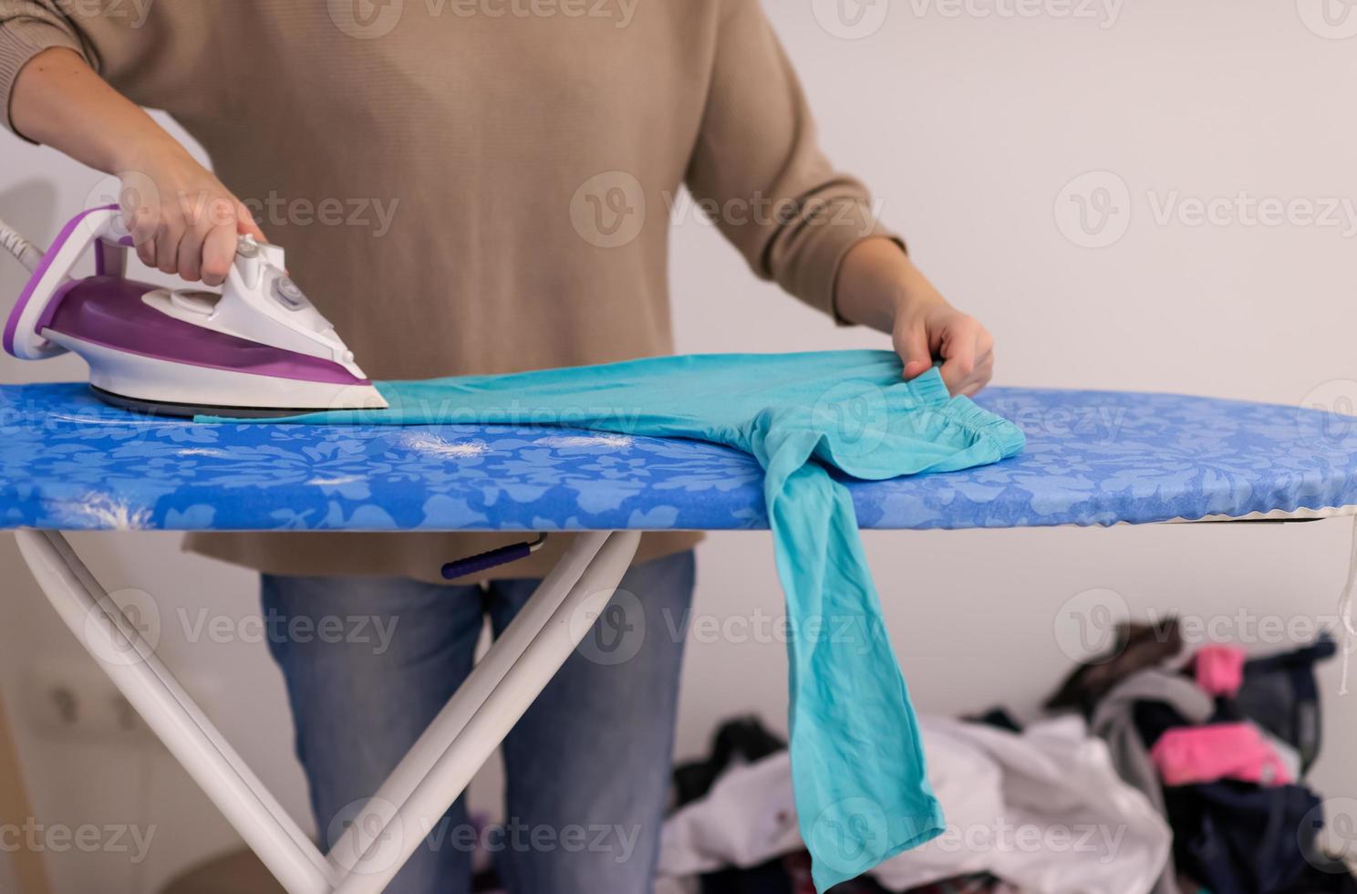 Red haired woman ironing clothes at home photo