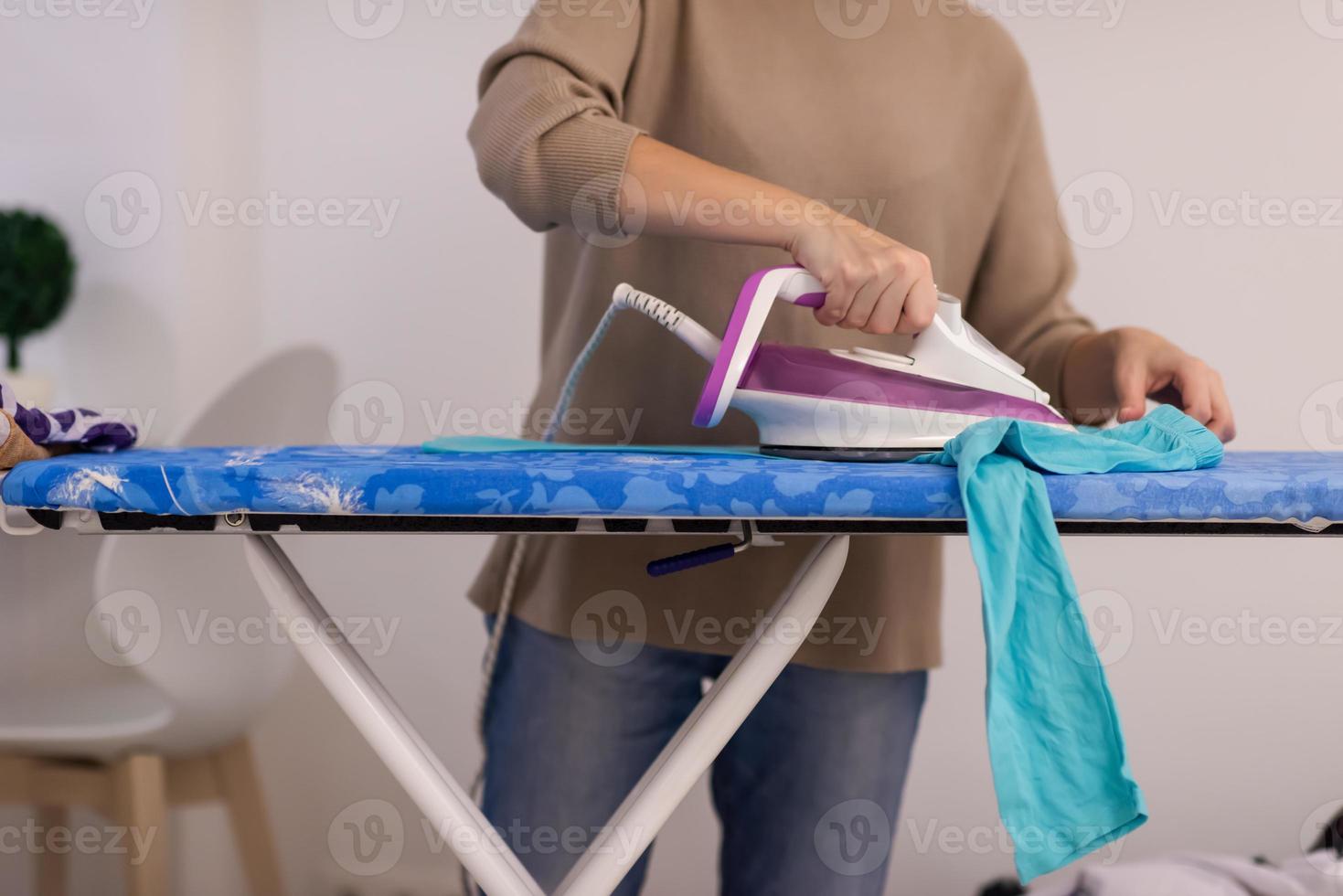 Red haired woman ironing clothes at home photo