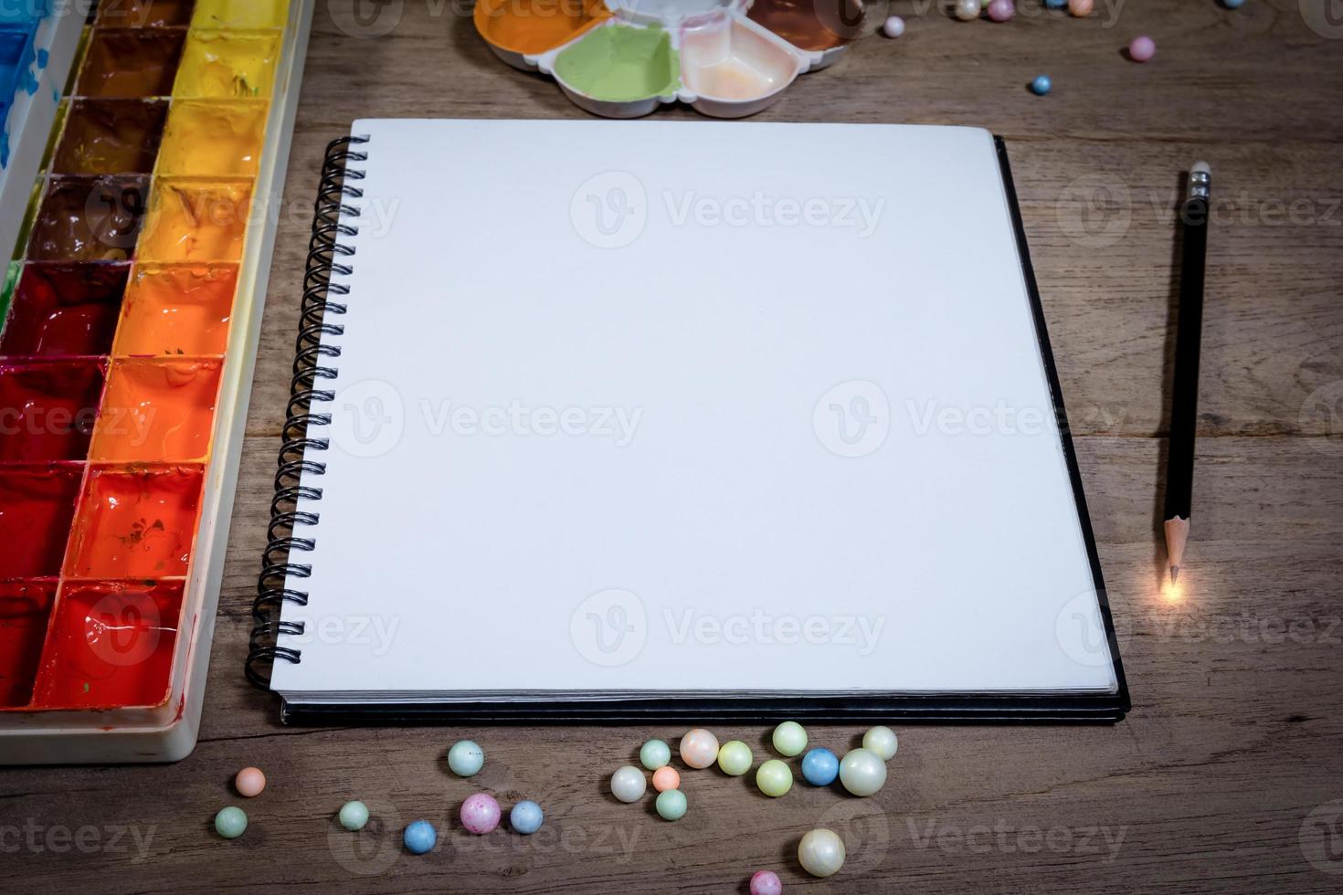 closeup open note book with tray colors on wood background photo