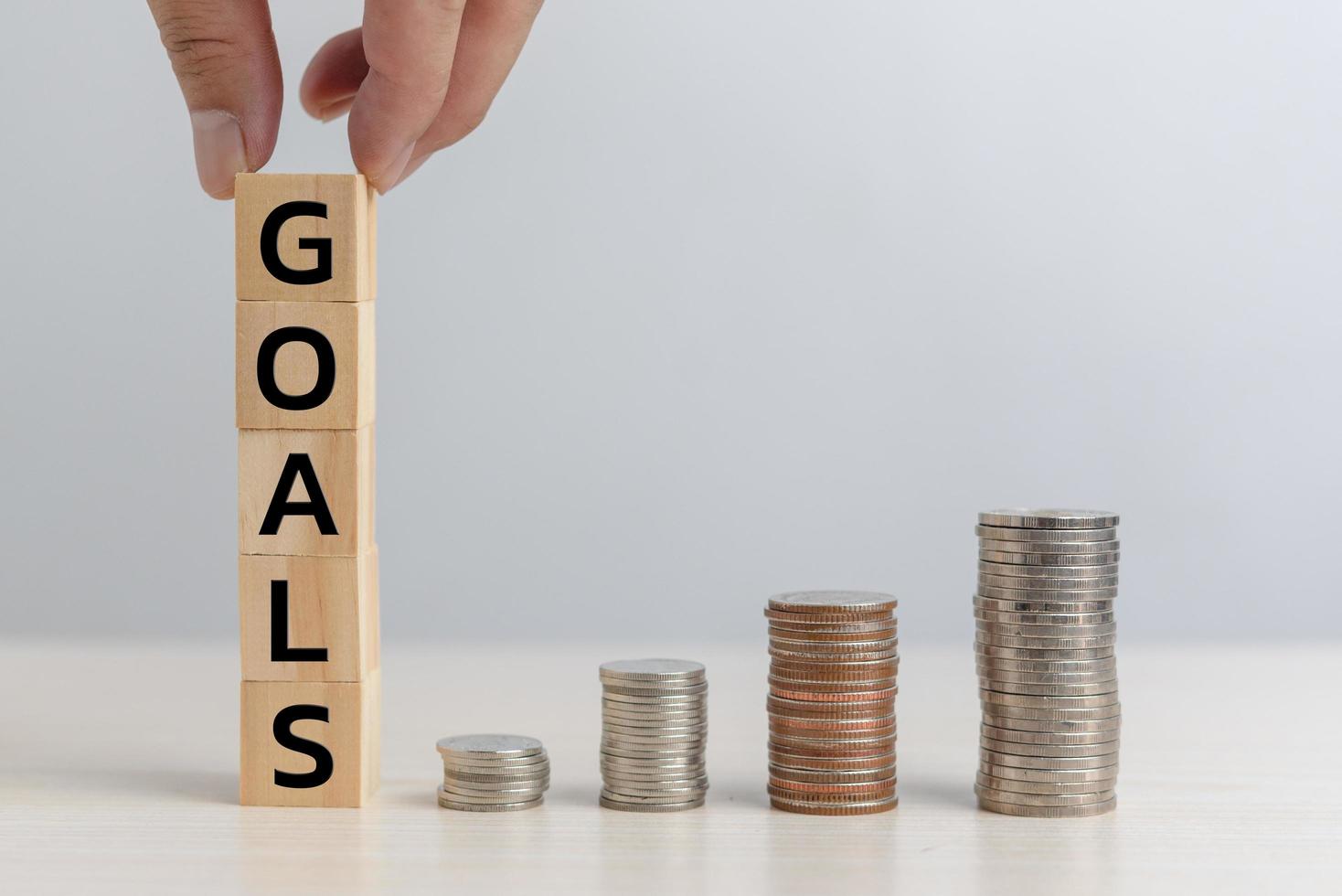 Hand hold wood cube block goals and money coin financial business economy investment and management accounting on table concept. photo