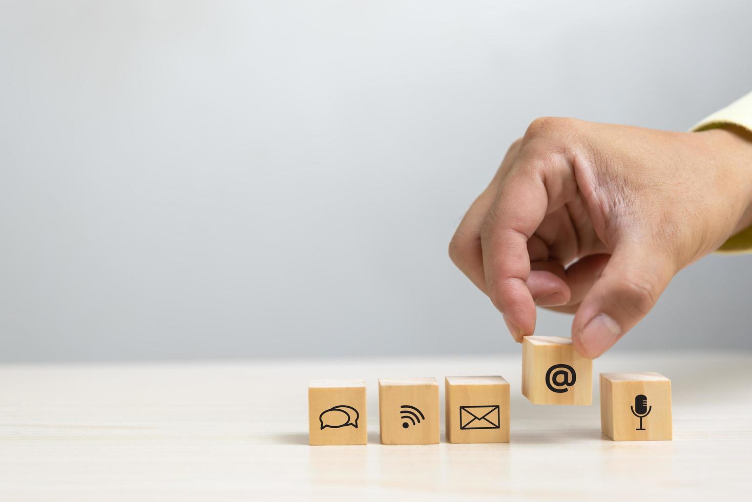 mano que sostiene el icono de bloque de cubo de madera comunicación servicio de red de Internet y correo electrónico del sitio web en el concepto de tabla. foto