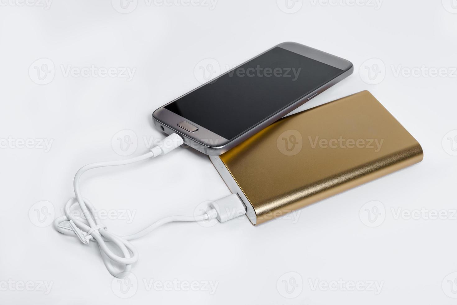 Golden powerbank with smart phone on background photo