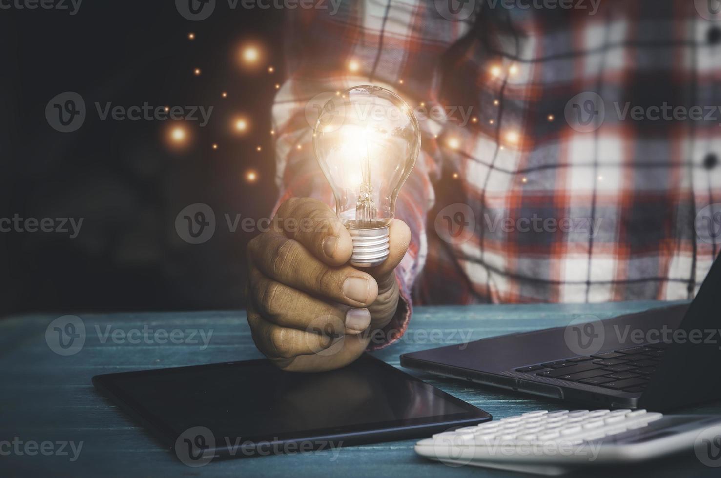 Hand holding light bulbs and book opening on wooden table.Creative thinking ideas for work on desk.searching for new ideas,Knowledge,successful, wisdom.Photo concept of knowledge and education. photo