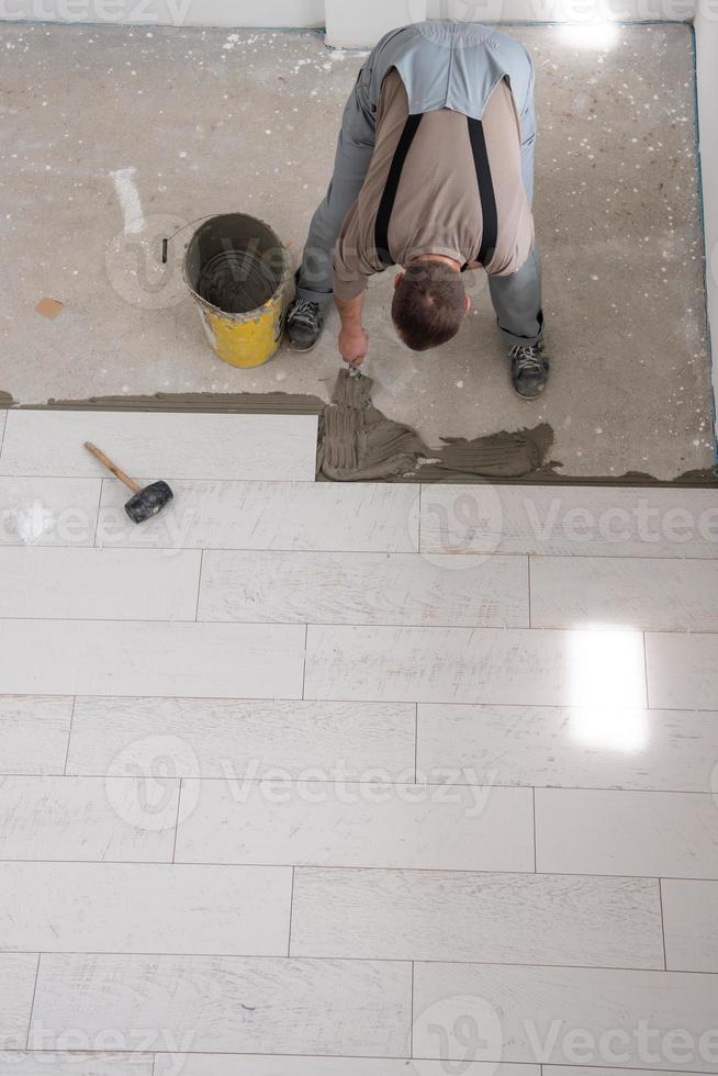 worker installing the ceramic wood effect tiles on the floor photo