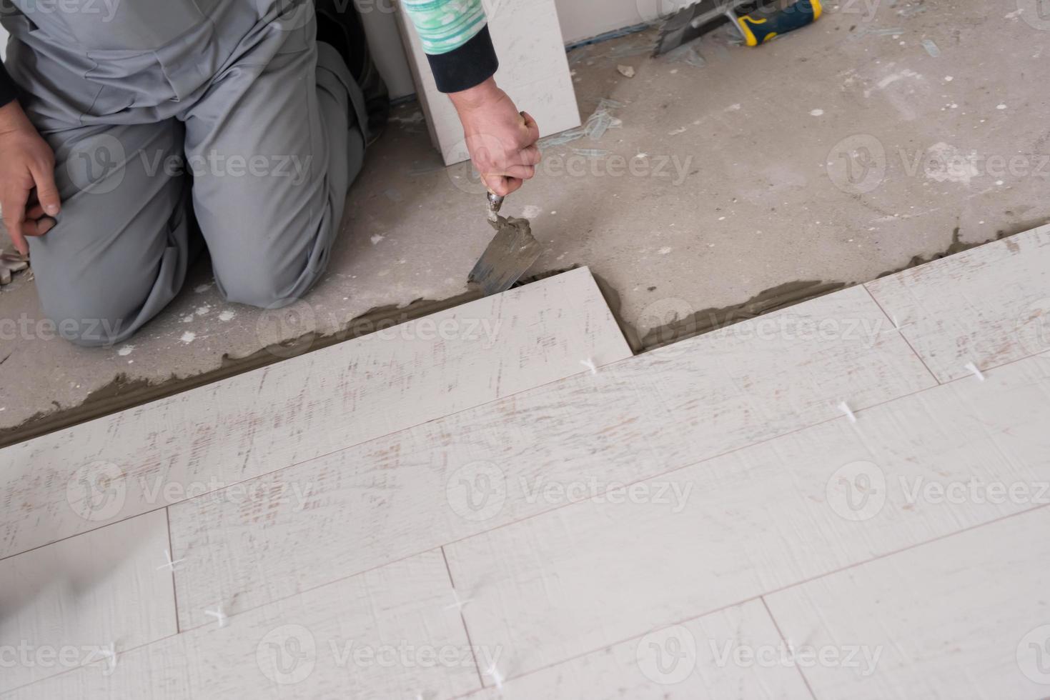 trabajador instalando las baldosas cerámicas con efecto madera en el suelo foto