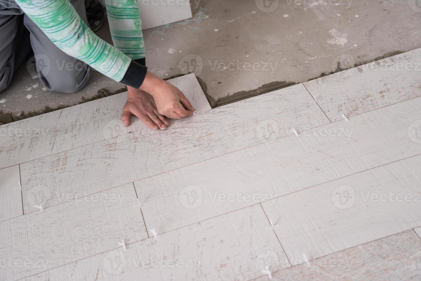 trabajador instalando las baldosas cerámicas con efecto madera en el suelo foto