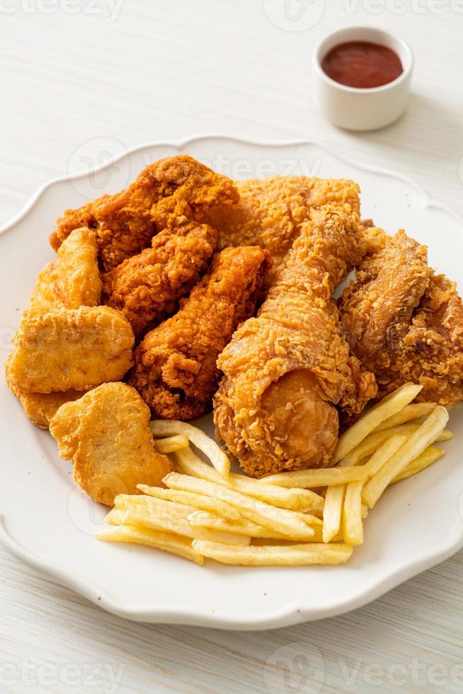 pollo frito con papas fritas y nuggets en un plato foto