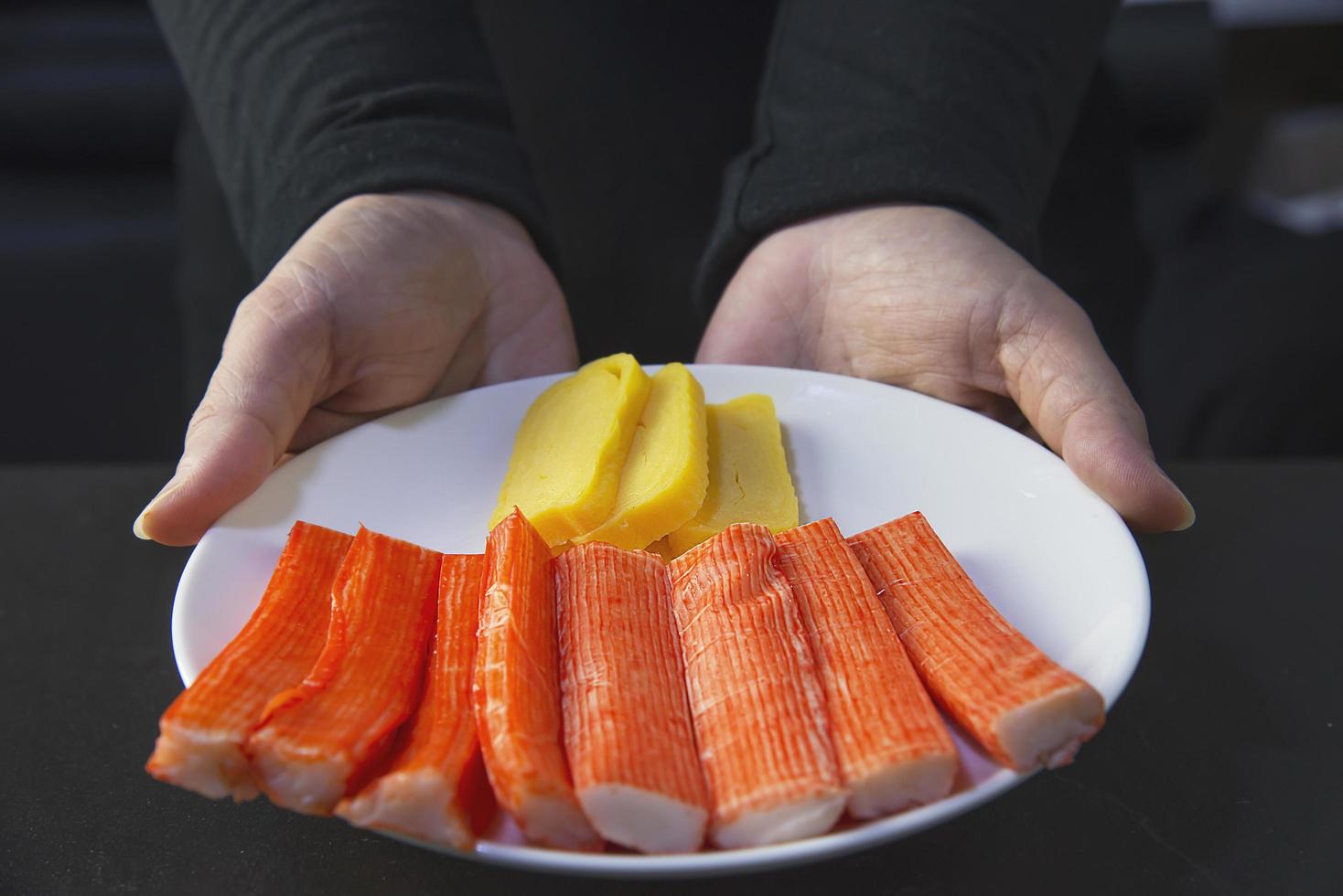 el chef está preparando palitos de cangrejo y tamagoyagi para hacer un menú de cocina japonesa, un rollo de sushi maki japonés que sirve en un restaurante oriental, varios conceptos variados de comida saludable mezclada de lujo foto