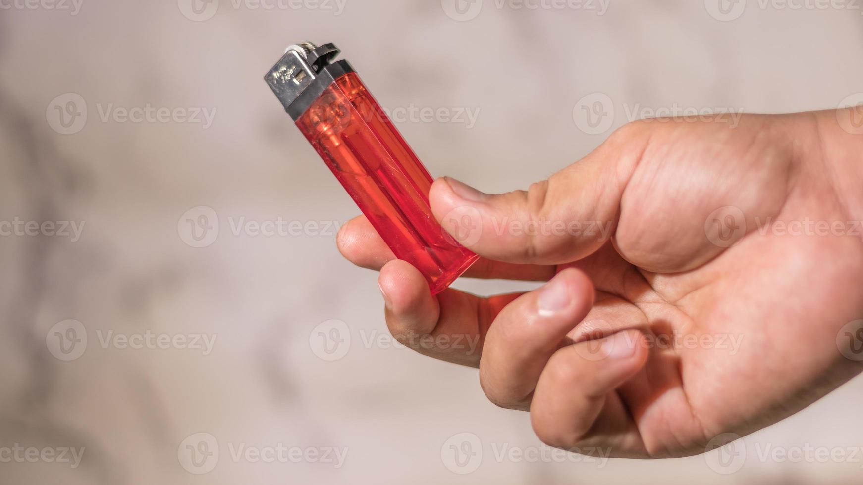 mano del hombre encendiendo un encendedor de cigarrillos contra un fondo brillante foto
