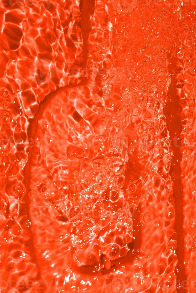 Defocus blurred transparent orange colored clear calm water surface texture with splashes and bubble. Trendy abstract nature background. Water wave in sunlight with copy space. Orange water drop color photo