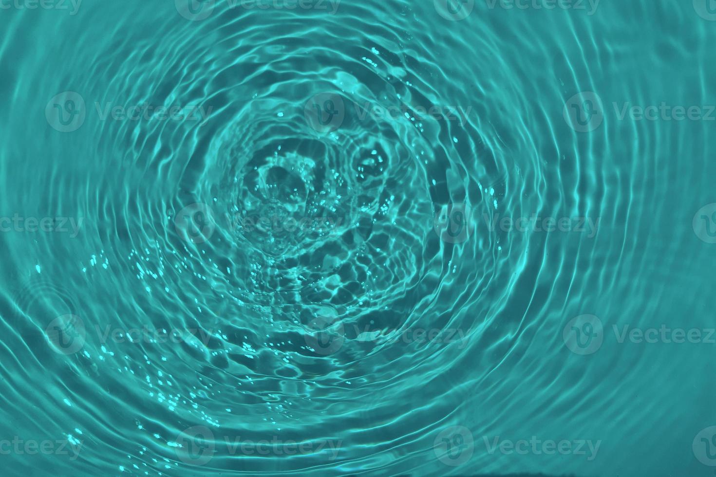 Defocus blurred transparent blue colored clear calm water surface texture with splashes and bubble. Trendy abstract nature background. Water wave in sunlight with copy space. Blue watercolor shining. photo