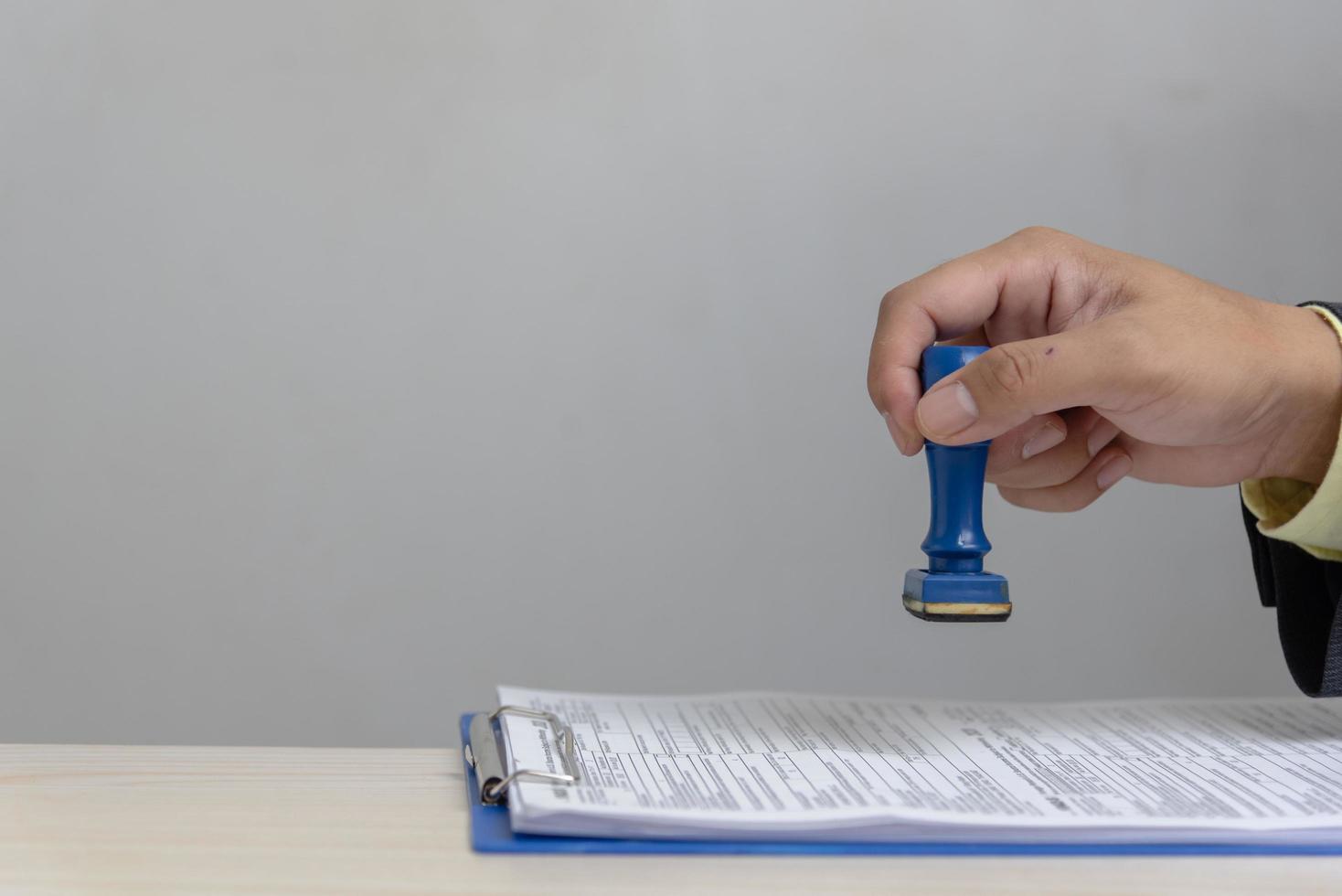 Man stamping approval of work finance banking or investment marketing documents on desk. photo
