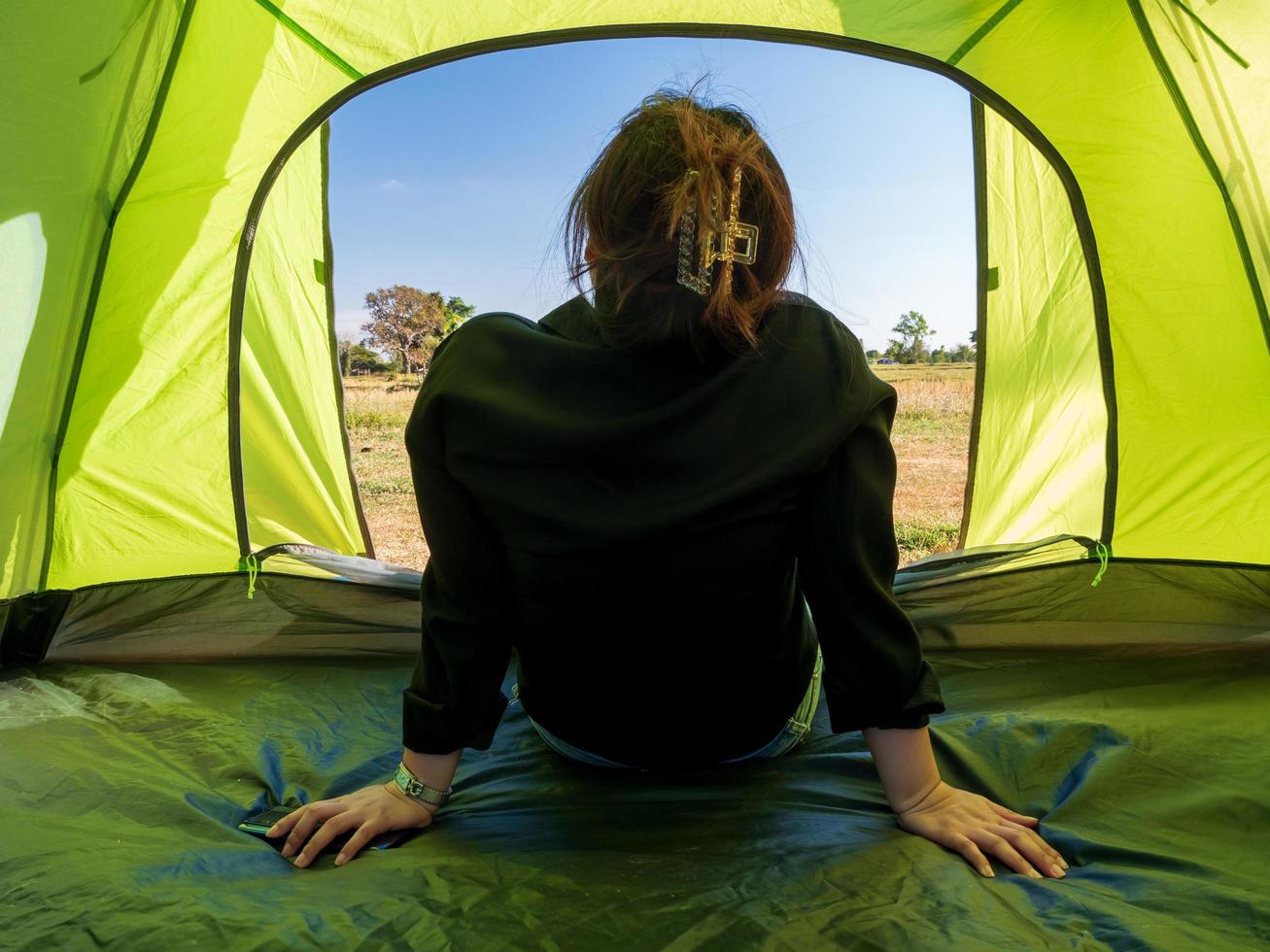 Asian female tourists are sitting happy free with green tent for traveler sits on  wide field, overlooking evening time Of Private area Thailand for camping getaway During long holiday for travel. photo