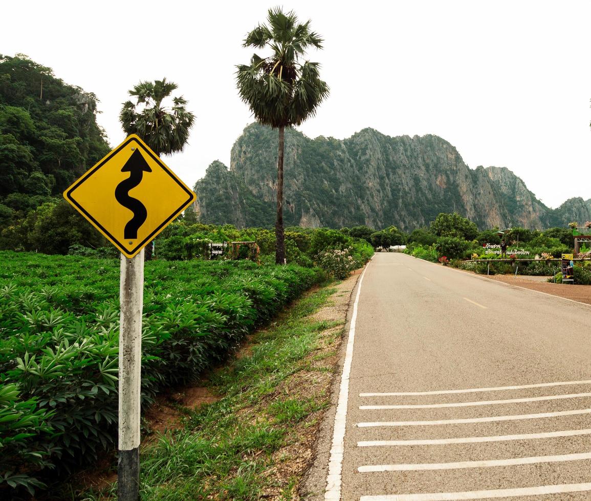 long road that travel through various village in rural Thailand passing through forest meadows and mountain on clear day blue sky white cloud in summer Suitable driving photo